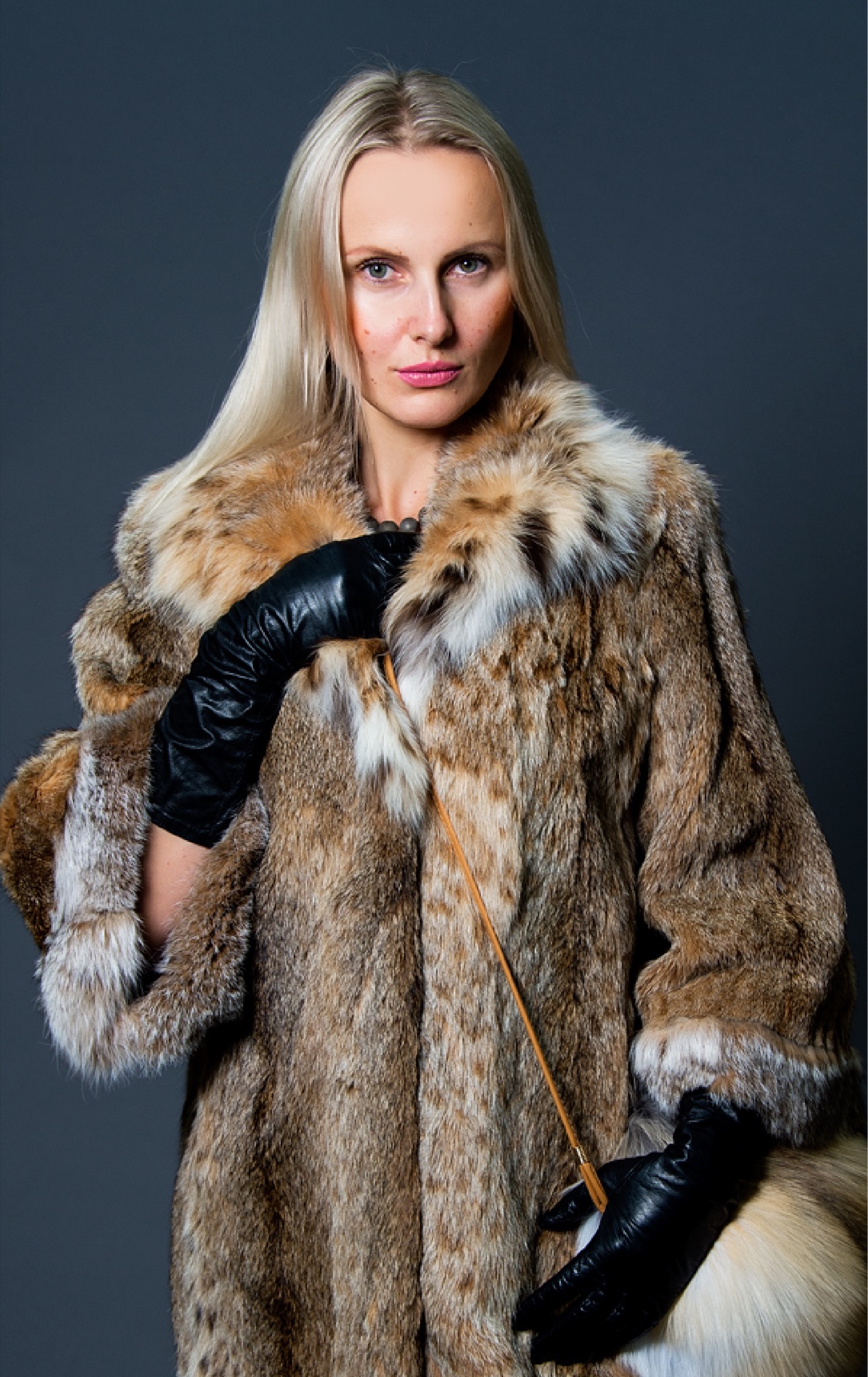 A blonde woman wearing leather gloves and furs